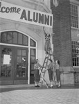 Female Students Hang "Welcome Alumni" Sign Outside Bibb Graves Hall 2 by unknown