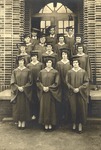 Graduates Dressed in Caps and Gowns Outside Brick Building by Russell Brothers Studio