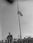 Dean Theron Montgomery Speaks from Podium Beneath Flag Flying at Half Mast by Opal R. Lovett