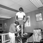 Trainer Mike Jackson Treats Football Player in Training Room 2 by Opal R. Lovett